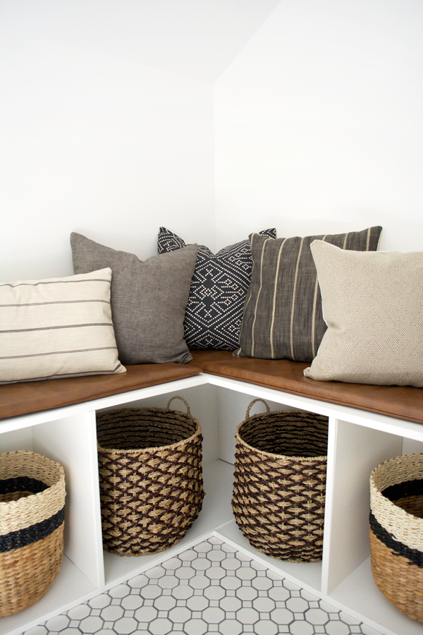 neutral pillows and baskets on a custom corner bench