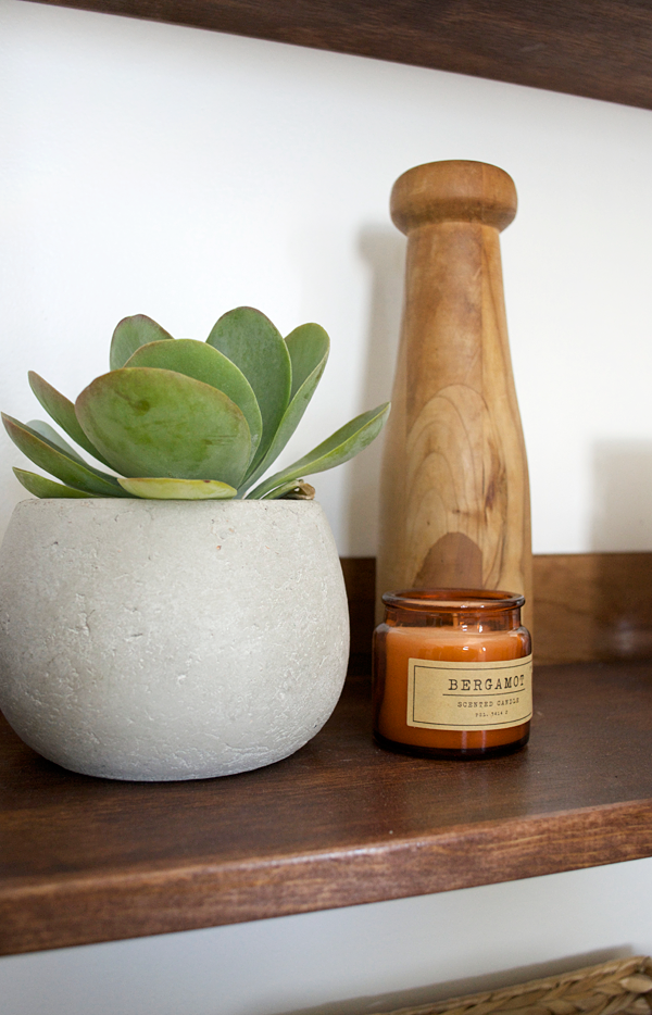 a concrete planter and brown glass candle in a bathroom