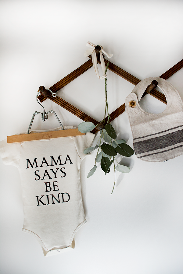 mama says be kind onesie hanging in nursery