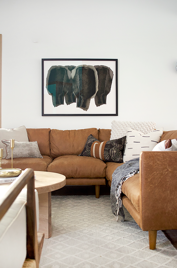 Leather sectional in living room with black abstract art